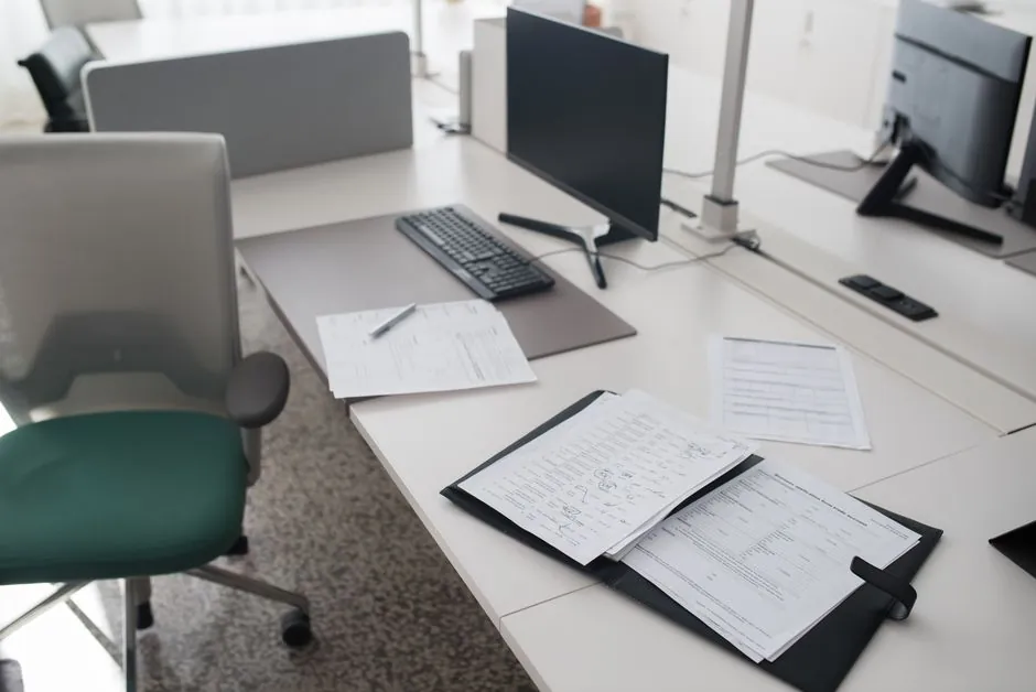Un bureau de bureau propre et organisé avec des documents, un ordinateur et une chaise dans un espace de travail moderne.