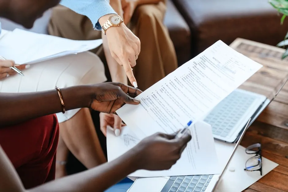 Groupe de professionnels passant en revue des documents lors d'une réunion de bureau, mettant l'accent sur le travail d'équipe et la stratégie.