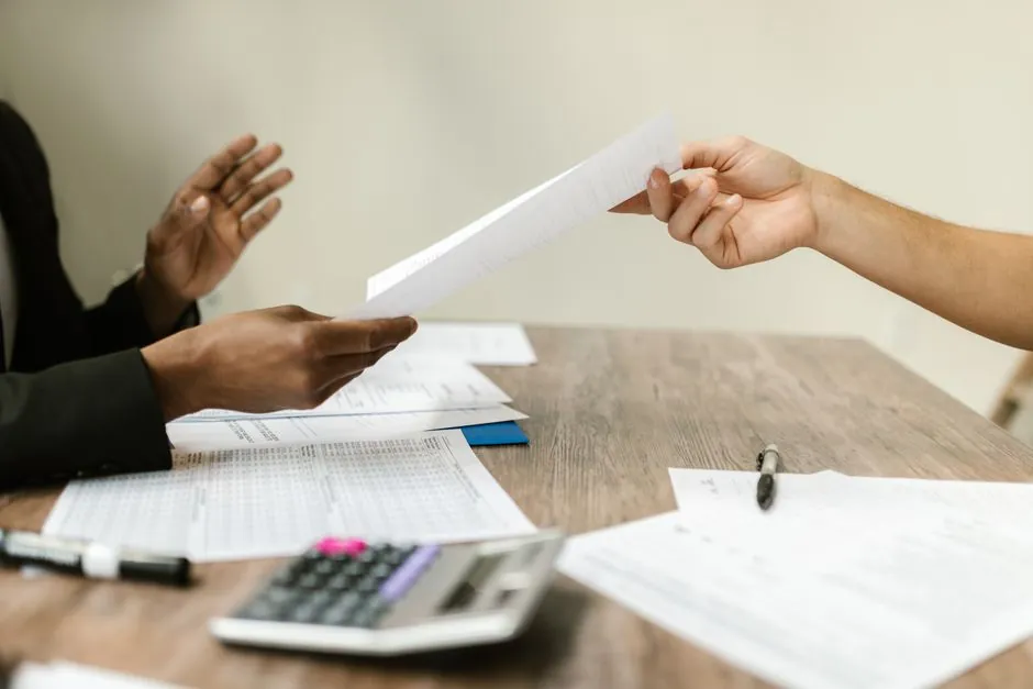 Deux professionnels échangeant des documents dans un cadre professionnel.