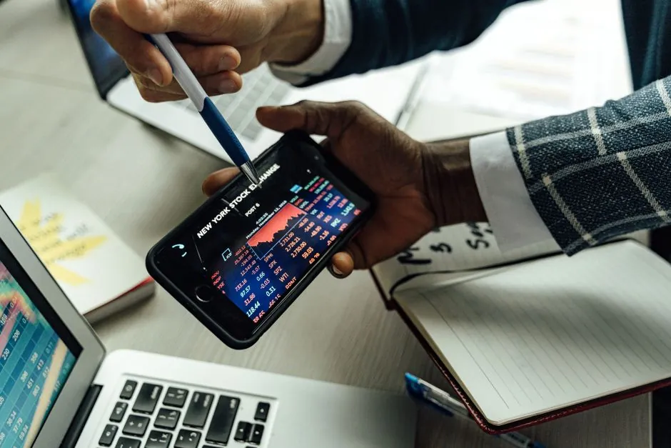 Des professionnels des affaires analysent les données de la bourse sur un smartphone dans un cadre de bureau.