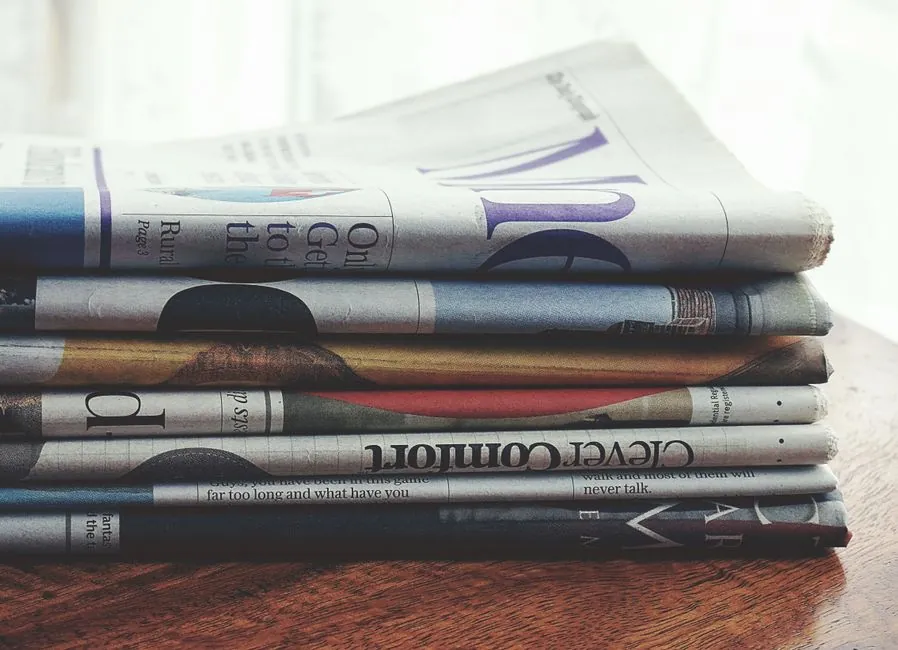 Une pile de journaux pliés posée sur une table en bois.